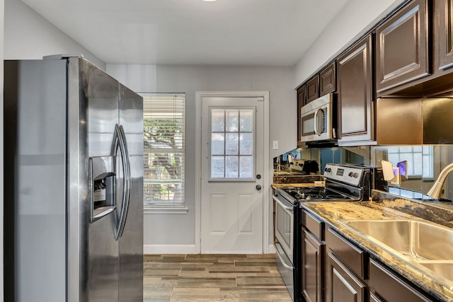10240 Regal Oaks Dr Unit C, Dallas, TX 75230 - kitchen with stainless steel appliances, dark brown cabinets, wood finished floors, a sink, and baseboards