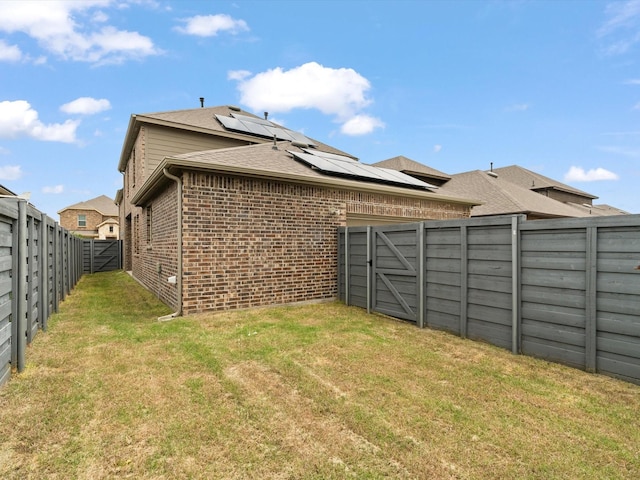 6020 Paddock Ln, Little Elm, TX 76227 - rear view of house featuring a gate, brick siding, solar panels, and a shingled roof