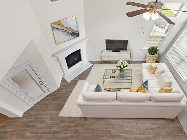 6020 Paddock Ln, Little Elm, TX 76227 - living room featuring wood finished floors, a ceiling fan, a fireplace with raised hearth, and baseboards