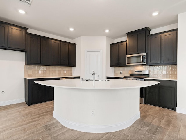 6020 Paddock Ln, Little Elm, TX 76227 - kitchen featuring stainless steel appliances, light countertops, a sink, an island with sink, and backsplash