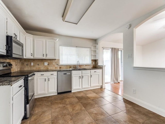 1804 Shreveport Trl, Plano, TX 75023 - kitchen featuring appliances with stainless steel finishes, arched walkways, decorative backsplash, a sink, and white cabinetry