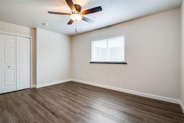 unfurnished bedroom with dark wood finished floors, baseboards, a closet, and a ceiling fan