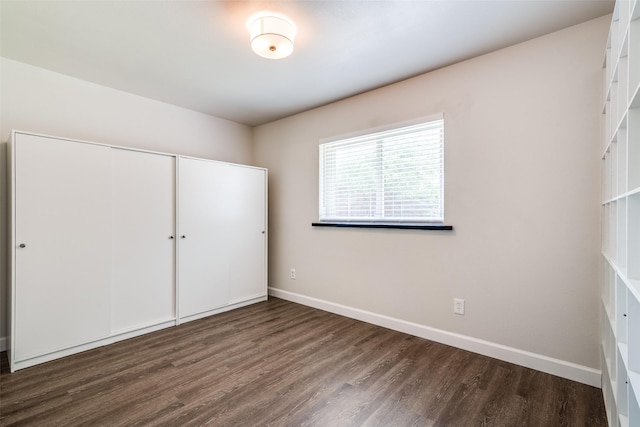 unfurnished bedroom featuring wood finished floors, a closet, and baseboards