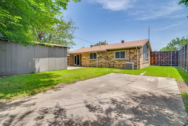 back of house featuring central AC unit, a patio area, an outbuilding, and brick siding