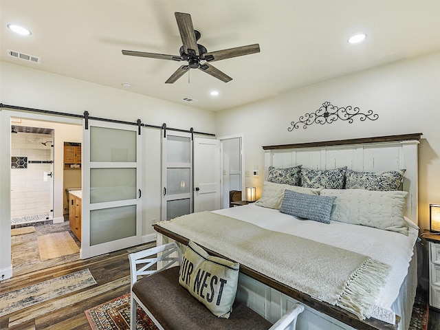 6025 Fm 902, Gainesville, TX 76240 - bedroom featuring a barn door, recessed lighting, dark wood-type flooring, a ceiling fan, and ensuite bath