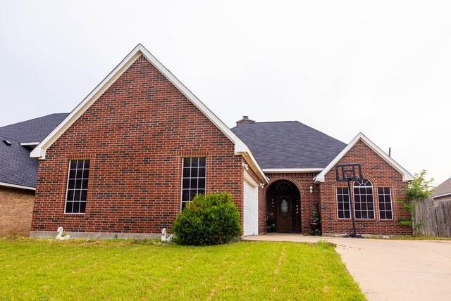 7506 Quail Springs Dr, Arlington, TX 76002 - view of front of home with brick siding, an attached garage, a front lawn, concrete driveway, and a chimney