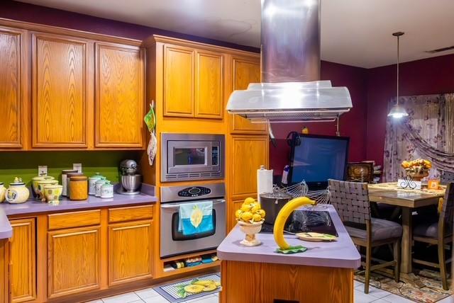 7506 Quail Springs Dr, Arlington, TX 76002 - kitchen with appliances with stainless steel finishes, island range hood, light countertops, and light tile patterned floors