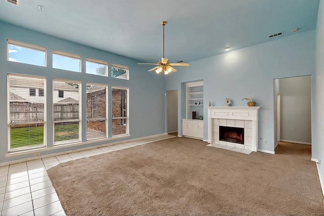 unfurnished living room featuring a fireplace, ceiling fan, tile patterned flooring, baseboards, and carpet floors