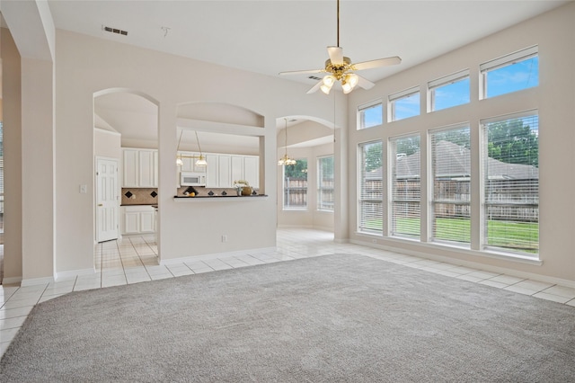 1221 Old Oak Trl, Flower Mound, TX 75028 - unfurnished living room featuring light tile patterned flooring, arched walkways, ceiling fan, baseboards, and a towering ceiling