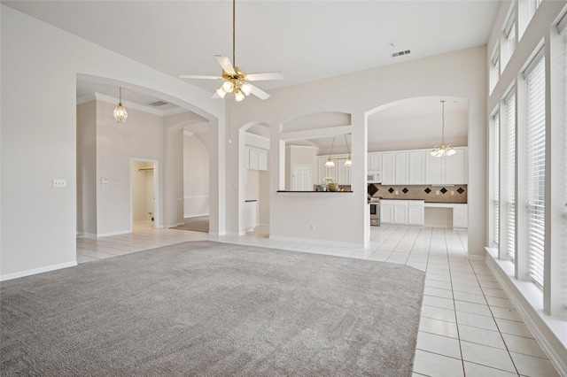 1221 Old Oak Trl, Flower Mound, TX 75028 - unfurnished living room featuring light tile patterned floors, arched walkways, plenty of natural light, a ceiling fan, and a towering ceiling