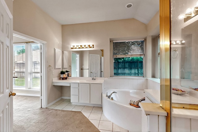 full bath featuring a garden tub, tile patterned floors, vanity, vaulted ceiling, and baseboards