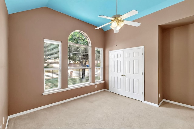 unfurnished bedroom featuring carpet floors, multiple windows, vaulted ceiling, a closet, and baseboards
