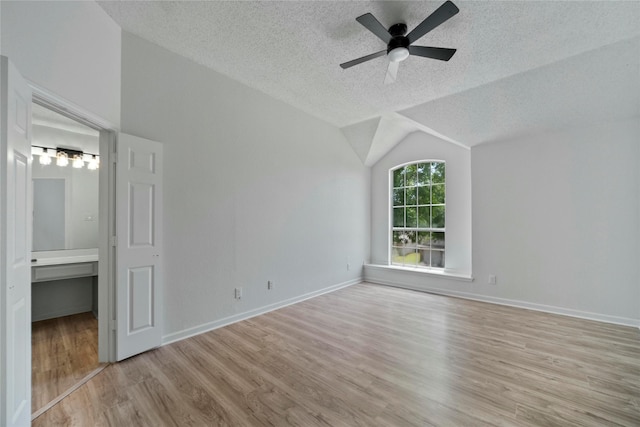 1100 Hyde Park Dr, Mckinney, TX 75069 - unfurnished bedroom featuring a textured ceiling, light wood finished floors, vaulted ceiling, baseboards, and connected bathroom