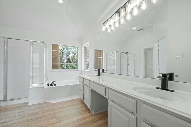 1100 Hyde Park Dr, Mckinney, TX 75069 - full bathroom with vaulted ceiling, a stall shower, double vanity, a bath, and wood finished floors