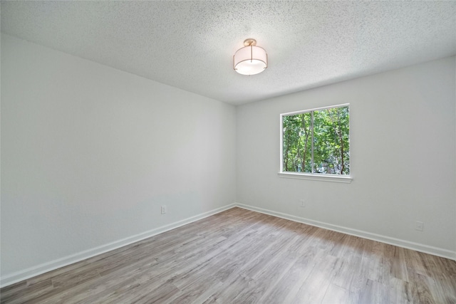 1100 Hyde Park Dr, Mckinney, TX 75069 - unfurnished room featuring wood finished floors, baseboards, and a textured ceiling
