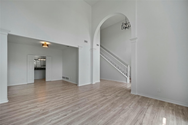1100 Hyde Park Dr, Mckinney, TX 75069 - spare room featuring light wood-style flooring, a high ceiling, baseboards, stairway, and arched walkways