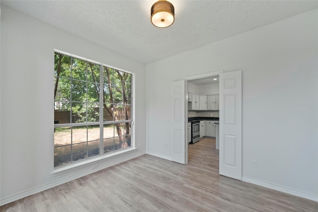 1100 Hyde Park Dr, Mckinney, TX 75069 - unfurnished room with baseboards, light wood-style floors, and a textured ceiling