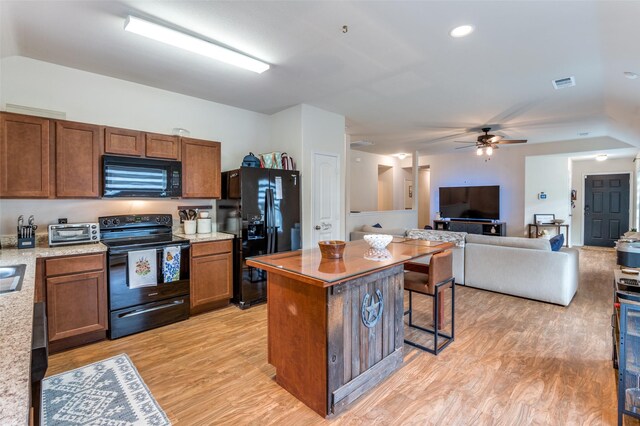 3504 Robin Rd, Ennis, TX 75119 - kitchen with black appliances, vaulted ceiling, light wood finished floors, a center island, and a ceiling fan
