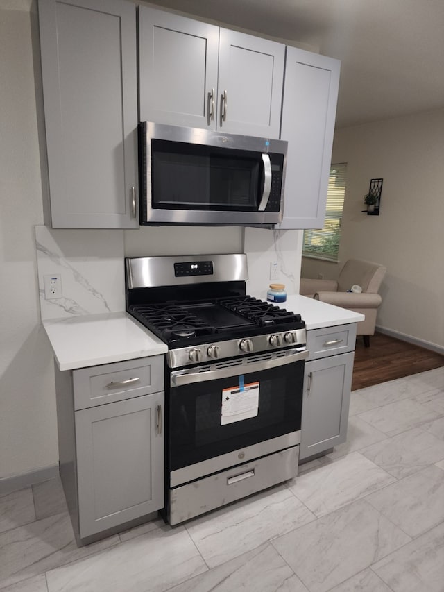 1104 Edgefield, Garland, TX 75040 - kitchen with appliances with stainless steel finishes, gray cabinets, light countertops, baseboards, and light marble finish flooring