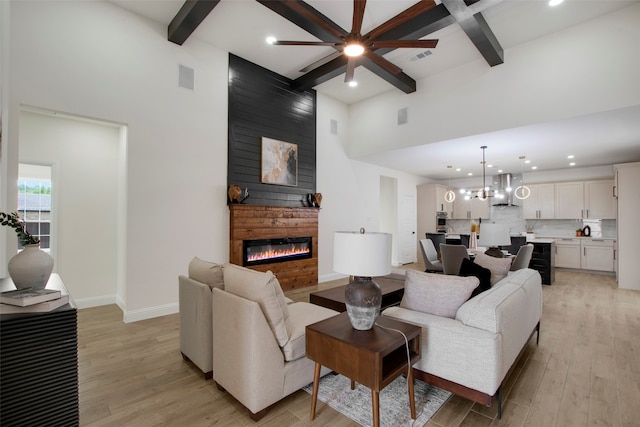 living room with recessed lighting, beam ceiling, ceiling fan, light wood-type flooring, and a fireplace