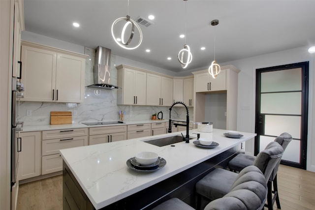 kitchen featuring wall chimney exhaust hood, a sink, light wood-style floors, decorative backsplash, and recessed lighting