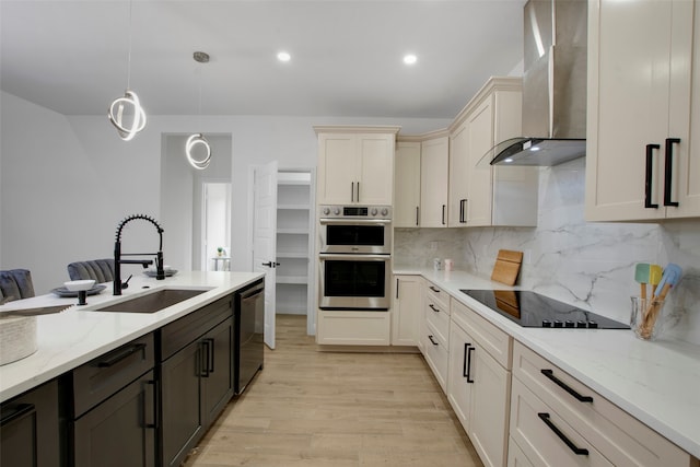 kitchen featuring wall chimney exhaust hood, black electric cooktop, dishwasher, stainless steel double oven, and a sink