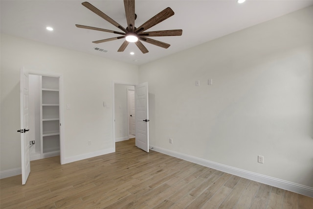 unfurnished bedroom with recessed lighting, light wood-type flooring, a walk in closet, baseboards, and a ceiling fan