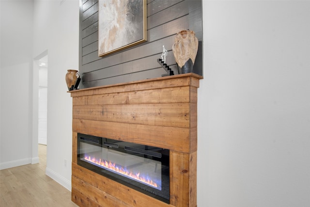 detailed view of a glass covered fireplace, baseboards, and wood finished floors