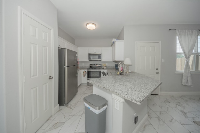 112 Wood St Unit A, Princeton, TX 75407 - kitchen featuring appliances with stainless steel finishes, light marble finish floors, a sink, a peninsula, and white cabinetry