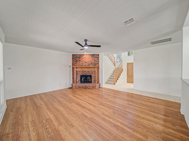 348 Kansas Trl, Murphy, TX 75094 - unfurnished living room with light wood-style flooring, a ceiling fan, a fireplace, and stairs