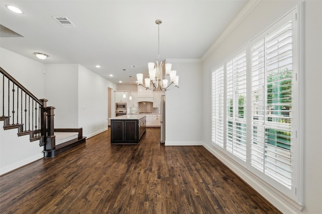 kitchen with appliances with stainless steel finishes, light countertops, a chandelier, baseboards, and a center island