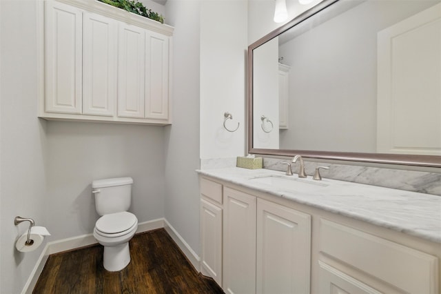 bathroom with wood finished floors, toilet, baseboards, and vanity