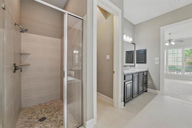 bathroom with a stall shower, a ceiling fan, vanity, and baseboards