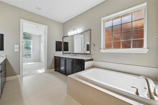 bathroom featuring vanity, a garden tub, and baseboards