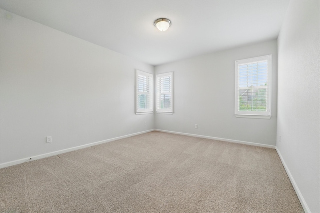 unfurnished room with light carpet and baseboards