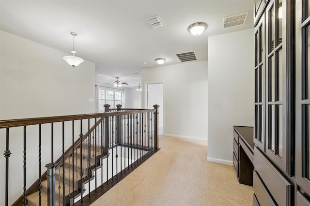 hallway with light colored carpet, baseboards, and an upstairs landing