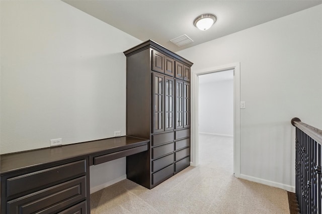 mudroom featuring light carpet, built in study area, and baseboards