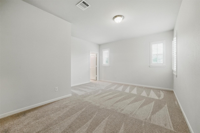 spare room featuring light carpet and baseboards