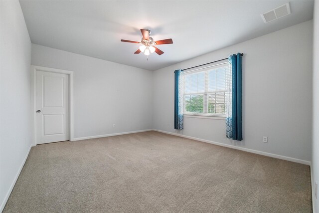 carpeted spare room featuring ceiling fan and baseboards