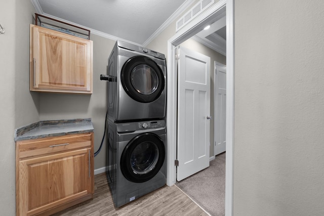 3266 Farm Rd Unit 1159, Clarksville, TX 75426 - laundry area with stacked washer / drying machine, crown molding, cabinet space, light wood-type flooring, and baseboards