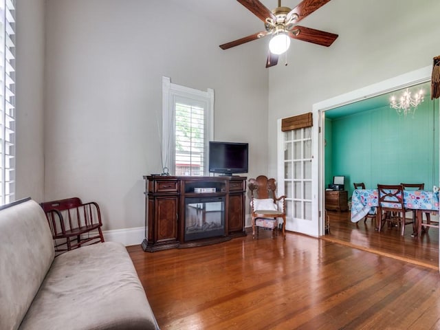 320 S Ward St, Italy, TX 76651 - living room featuring wood finished floors, a ceiling fan, a high ceiling, baseboards, and a chandelier