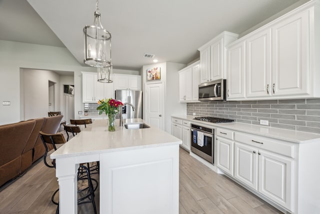 3120 Pioneer Path, Little Elm, TX 75068 - kitchen featuring stainless steel appliances, a sink, a kitchen bar, light wood-style floors, and tasteful backsplash