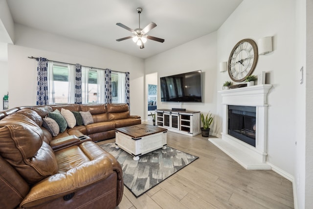 3120 Pioneer Path, Little Elm, TX 75068 - living area with a ceiling fan, light wood finished floors, a fireplace with raised hearth, and baseboards