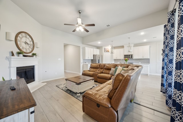 3120 Pioneer Path, Little Elm, TX 75068 - living room with light wood-type flooring, a ceiling fan, a fireplace with raised hearth, baseboards, and recessed lighting