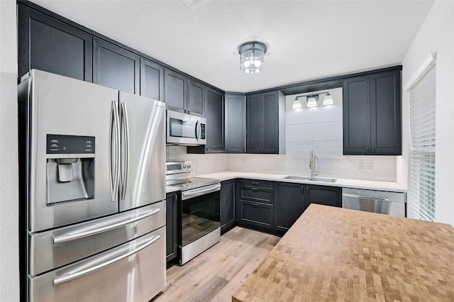 609 E Martin Ln, Sherman, TX 75090 - kitchen with appliances with stainless steel finishes, a sink, light wood-style floors, decorative backsplash, and light countertops