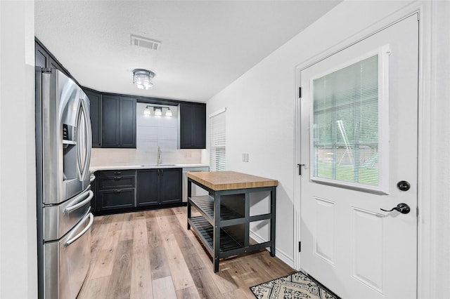609 E Martin Ln, Sherman, TX 75090 - kitchen with stainless steel appliances, a sink, light countertops, light wood-type flooring, and backsplash