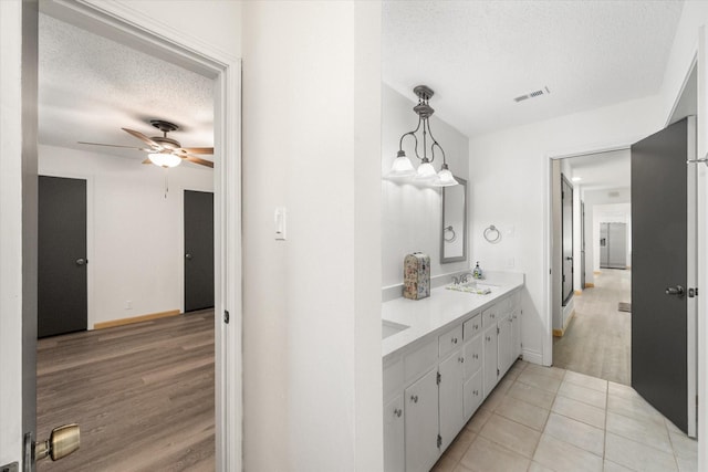 2000 Stacey Ct, Arlington, TX 76013 - bathroom featuring a textured ceiling, double vanity, ceiling fan, wood finished floors, and baseboards
