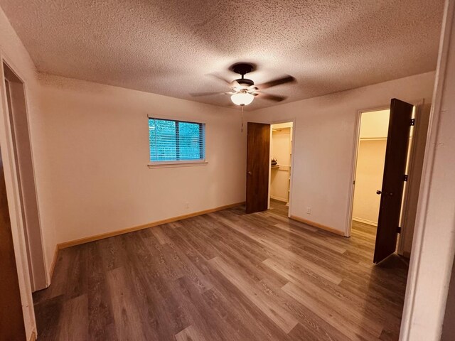 2000 Stacey Ct, Arlington, TX 76013 - unfurnished bedroom featuring wood finished floors, a textured ceiling, a spacious closet, and baseboards