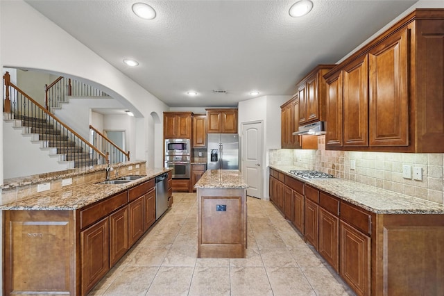 6824 San Fernando Dr, Fort Worth, TX 76131 - kitchen featuring stainless steel appliances, a kitchen island with sink, under cabinet range hood, a sink, and arched walkways