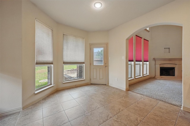 6824 San Fernando Dr, Fort Worth, TX 76131 - entryway with plenty of natural light, light tile patterned floors, a fireplace with raised hearth, and arched walkways